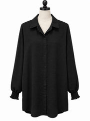 Svart tunika på skräddardocka, framifrån, med knäppning, bred krage och smockade manchetter | Caramelle Fashion | Lilla Hem