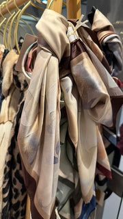 Sjal i beige och brunt hängande på trähängare, visar mjukt vävt material och färgskiftningar | L8 Fashion | Lilla Hem