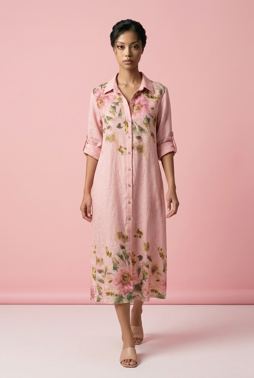 Modell bär rosa skjortklänning med blommigt tryck, sett framifrån mot rosa bakgrund | Miss Azur | Lilla Hem
