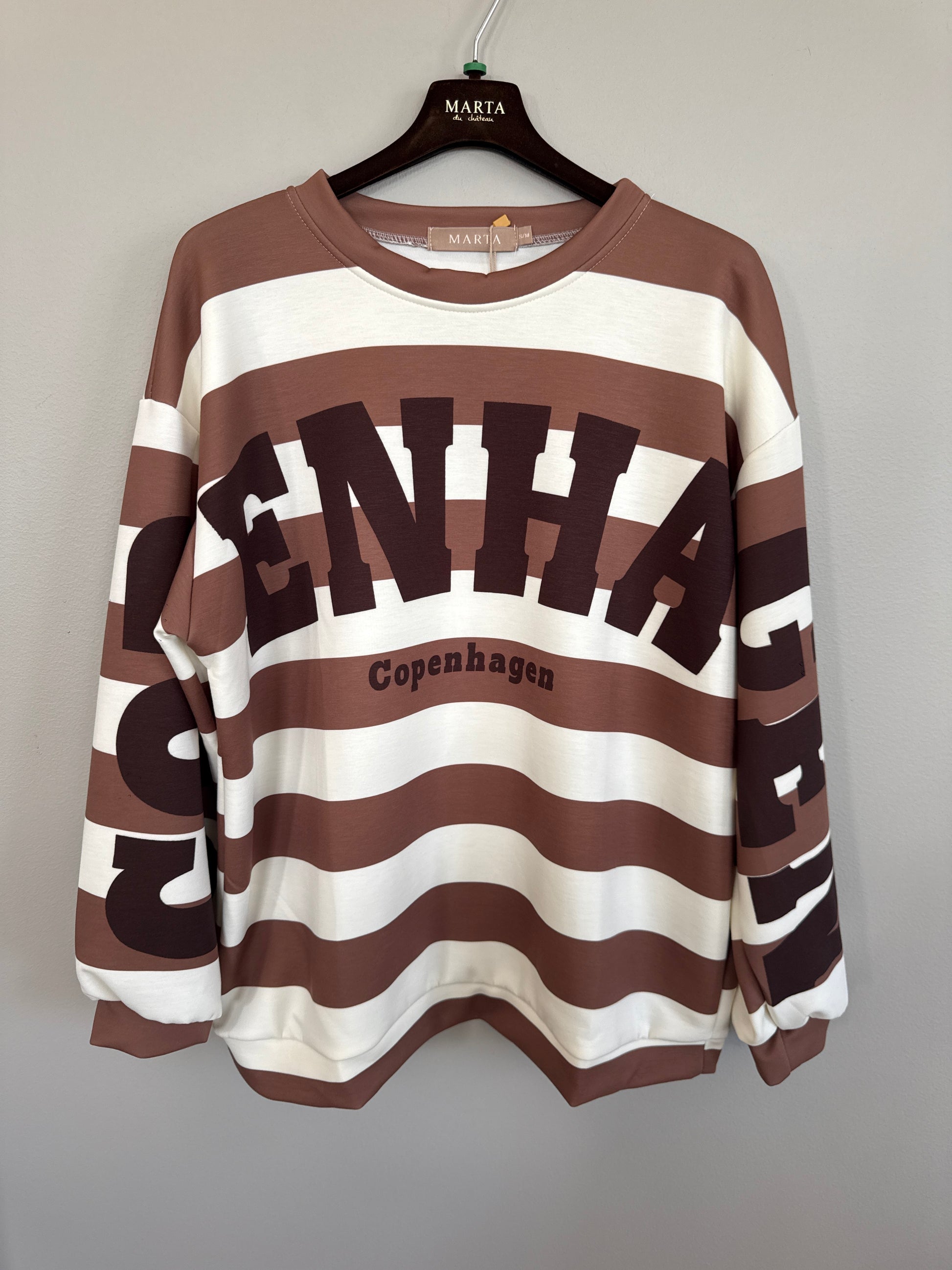Sweatshirt i brunt och vitt med grafiskt tryck och "Copenhagen"-text, hängande på galge framifrån | MARTA du Chateau | Lilla Hem