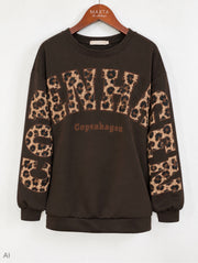 Svart sweatshirt med leopardmönstrad text och tryck på bröstet och armarna, hängande på träbygel | MARTA du Chateau | Lilla Hem