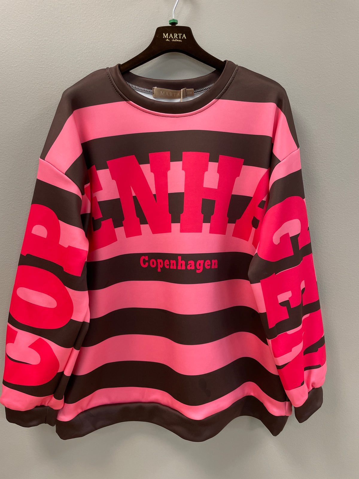 Sweatshirt i brunt och rosa med horisontella ränder, grafiskt tryck och "Copenhagen"-text, hängande på galge | MARTA du Chateau | Lilla Hem