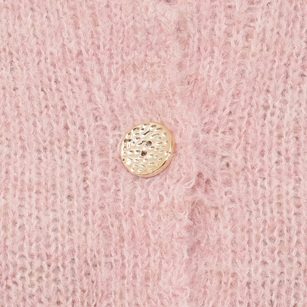 Närbild av rosa stickad trikå med guldknapp med texturerad yta | MARTA du Chateau | Lilla Hem