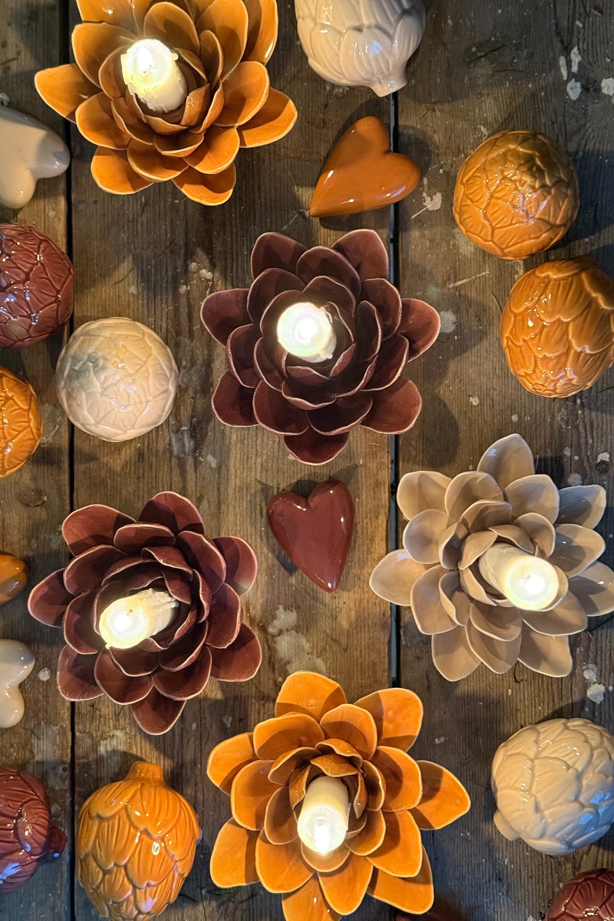 Blomformade ljuslyktor i orange, röd och beige på mörk träbakgrund, sett från ovan | Mitt och Ditt | Lilla Hem