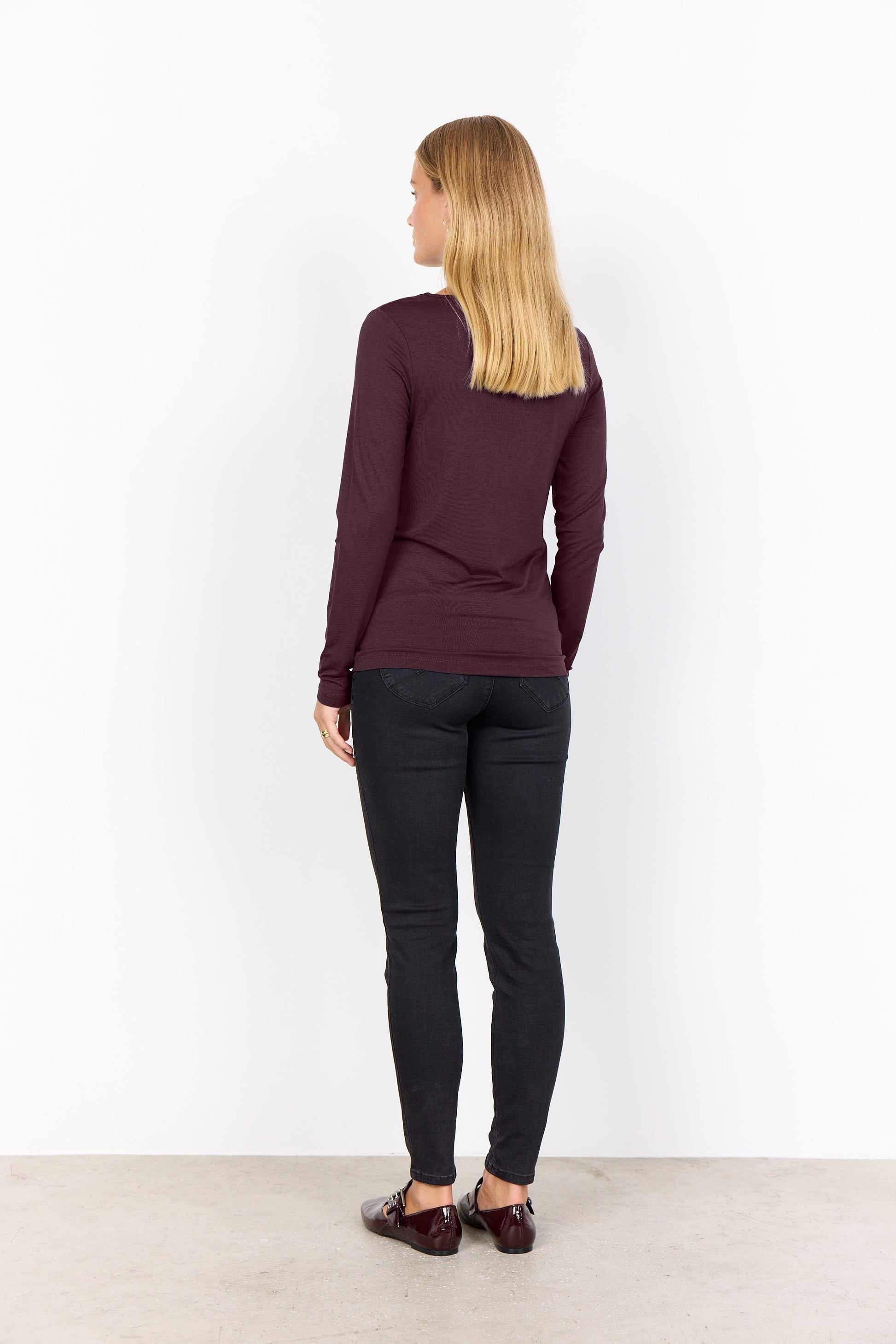 Modell bär burgundy långärmad tröja och svarta jeans, sedd från sidan bakifrån | Soya Concept | Lilla Hem