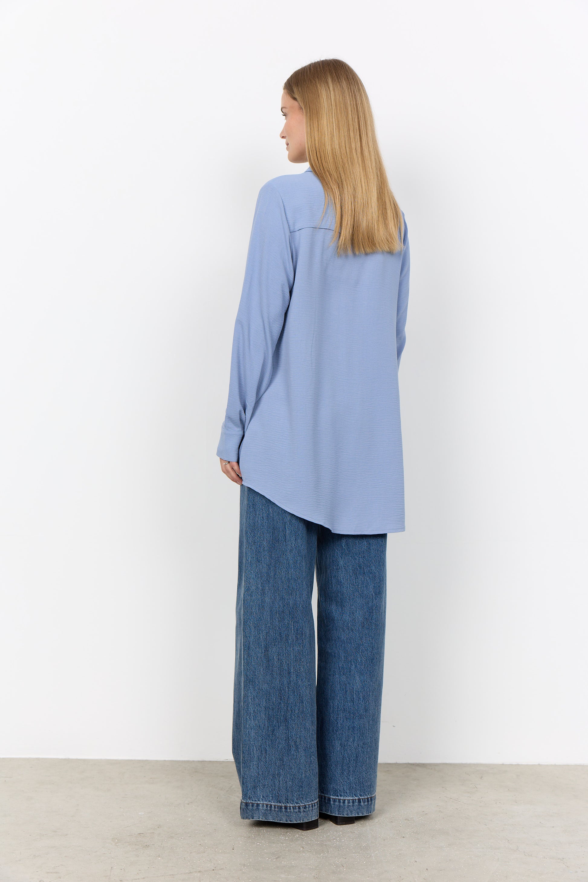 Modell bär ljusblå skjorta och vida jeans, sedd från sidan bakåt | Soya Concept | Lilla Hem