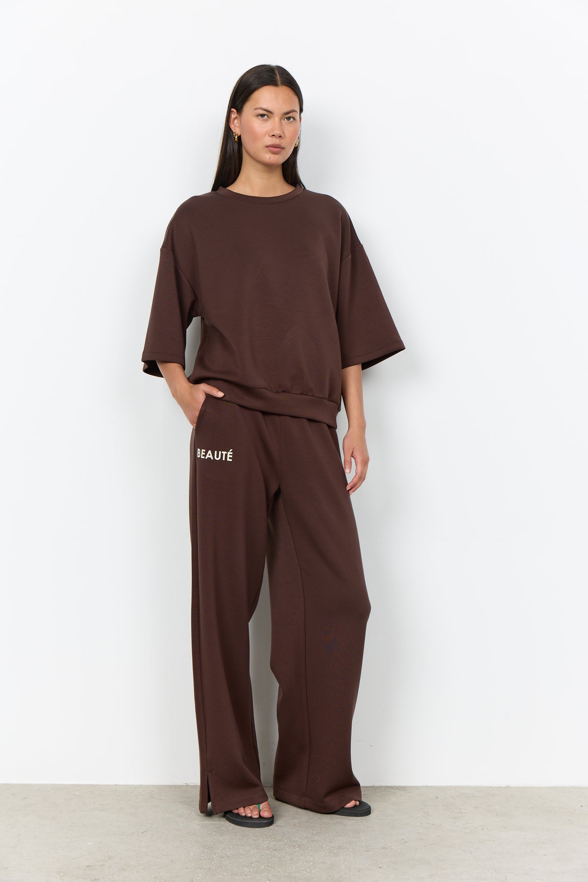 Modell bär brunt set med oversized t-shirt och vida byxor med "BEAUTÉ"-text, sett framifrån | Soya Concept | Lilla Hem