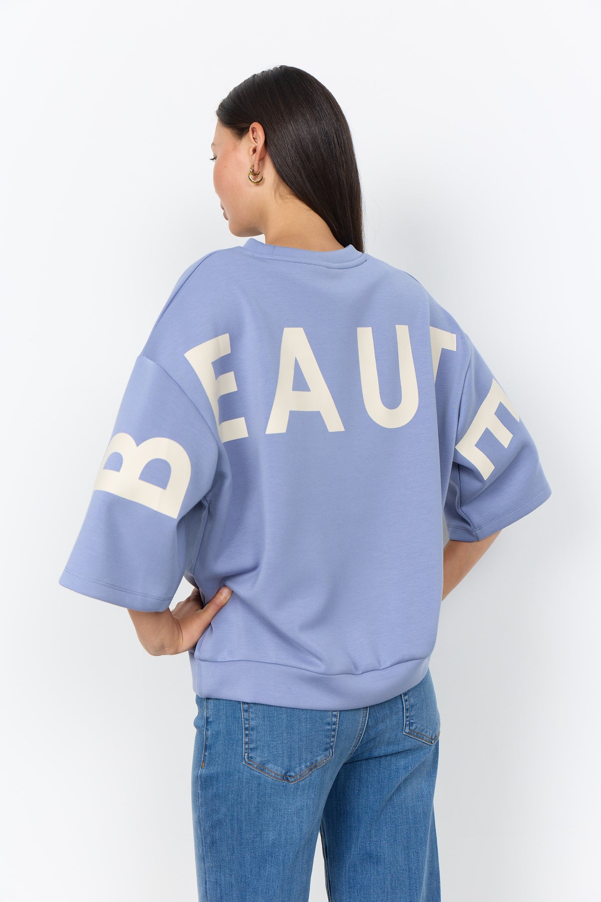 Modell bär blå sweatshirt med beige textprint på ryggen, sett från baksidan | Soya Concept | Lilla Hem