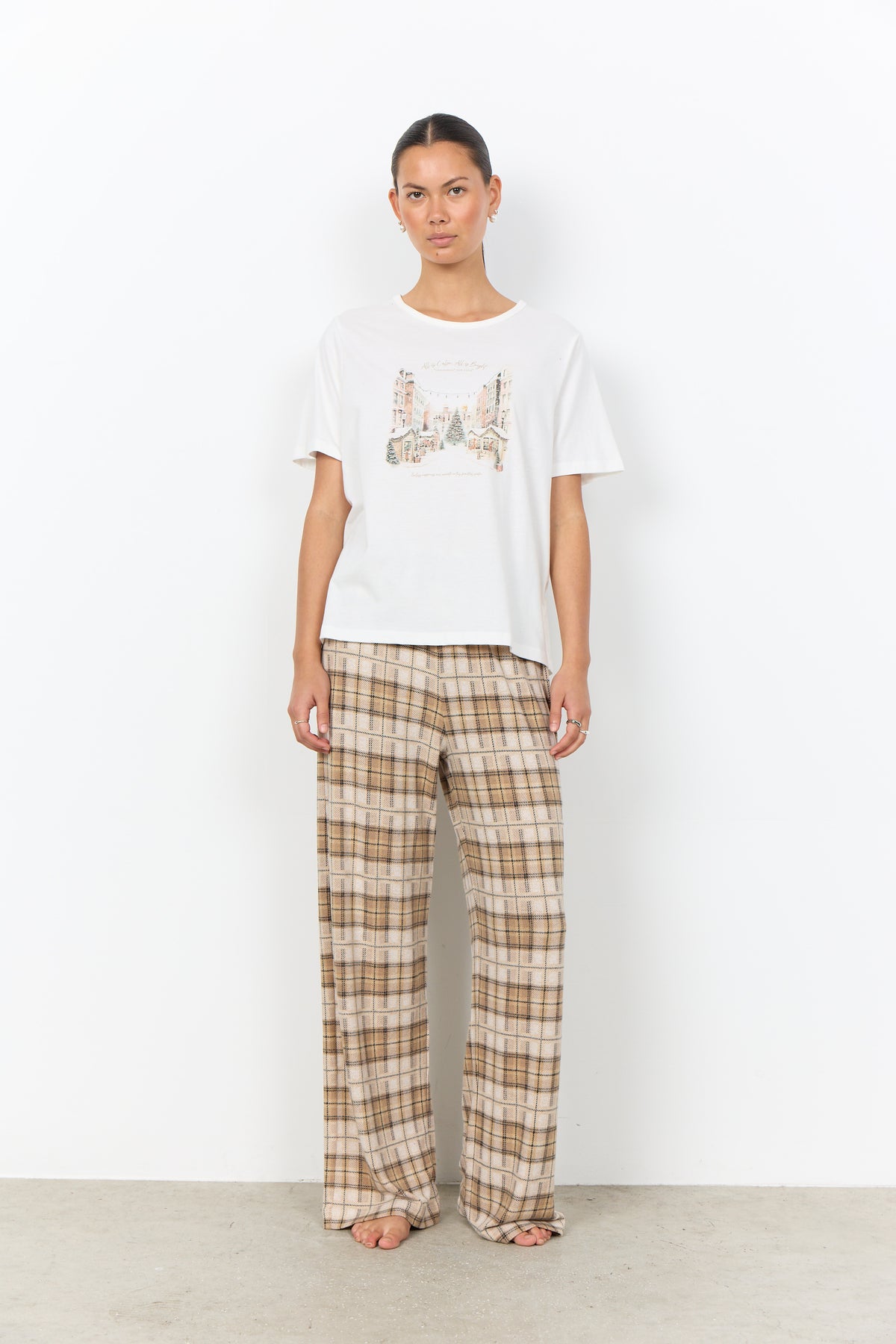 Modell bär vit t-shirt med stadsmotiv och rutiga byxor i beige och brunt, framifrån | Soya Concept | Lilla Hem