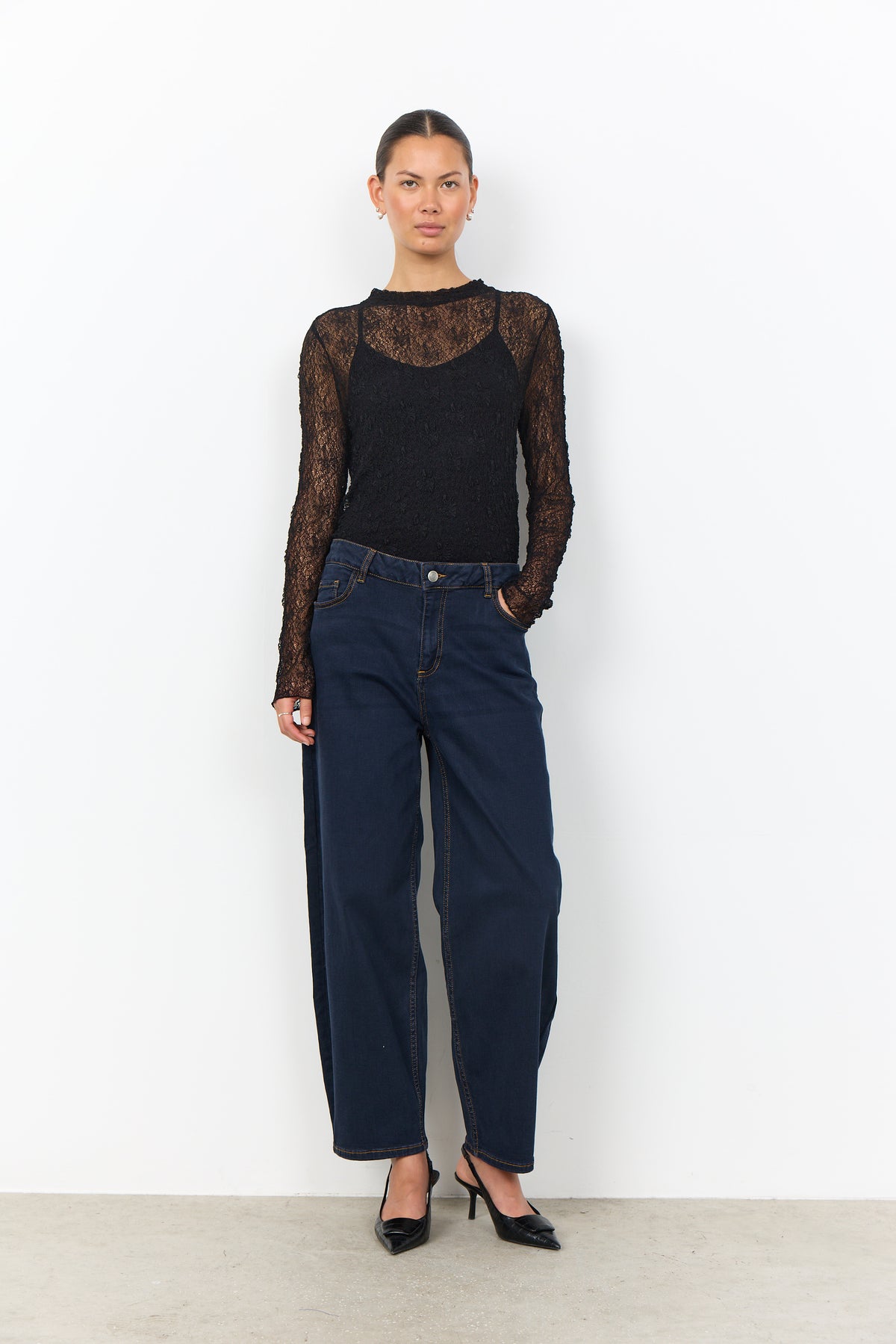 Modell bär svart spetsblus med långa ärmar och mörkblå jeans, sett framifrån mot vit bakgrund | Soya Concept | Lilla Hem