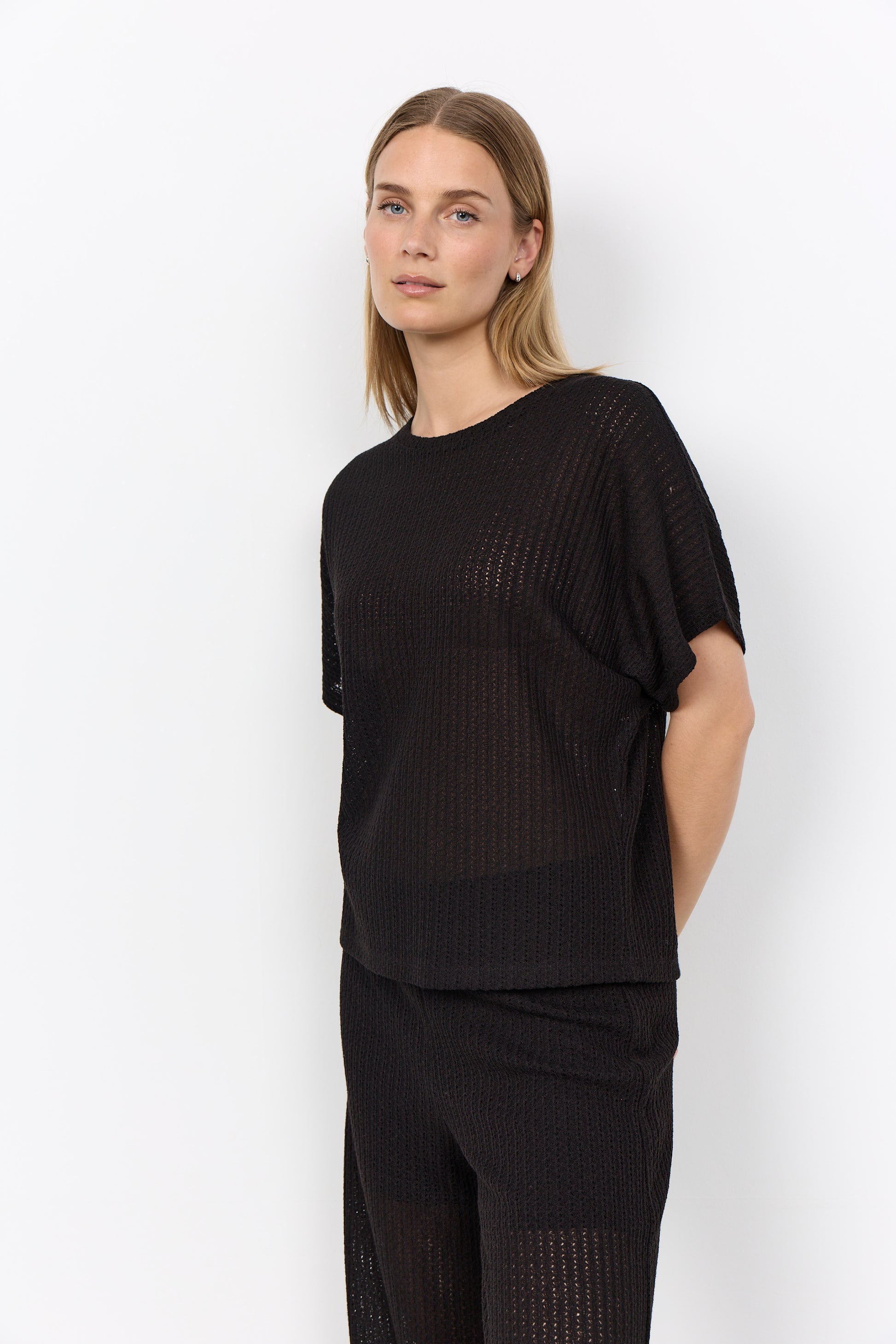 Modell bär svart ribbad t-shirt med korta ärmar sett från sidan mot vit bakgrund | Soya Concept | Lilla Hem