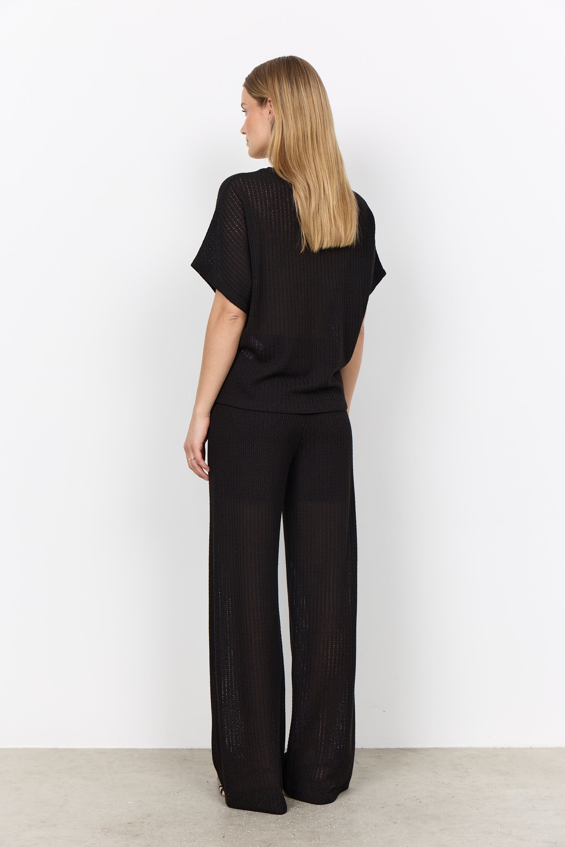 Modell bär svart ribbad set med kort t-shirt och vida byxor, sedd från sidan bakåt | Soya Concept | Lilla Hem