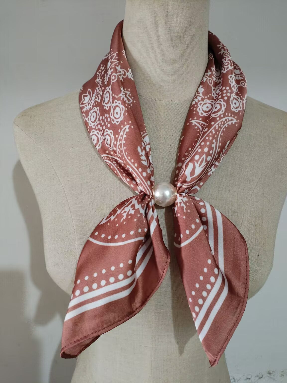 Scarf med vitt paisleymönster på rostfärgad botten, knuten runt hals med pärla | tim & simonsen | Lilla Hem
