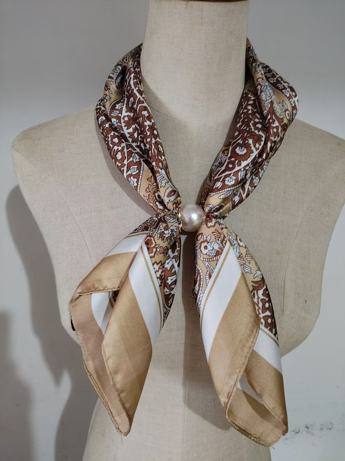 Scarf med brunt blommigt mönster och beige ändar, fäst med pärla runt halsen på mannekäng | tim & simonsen | Lilla Hem