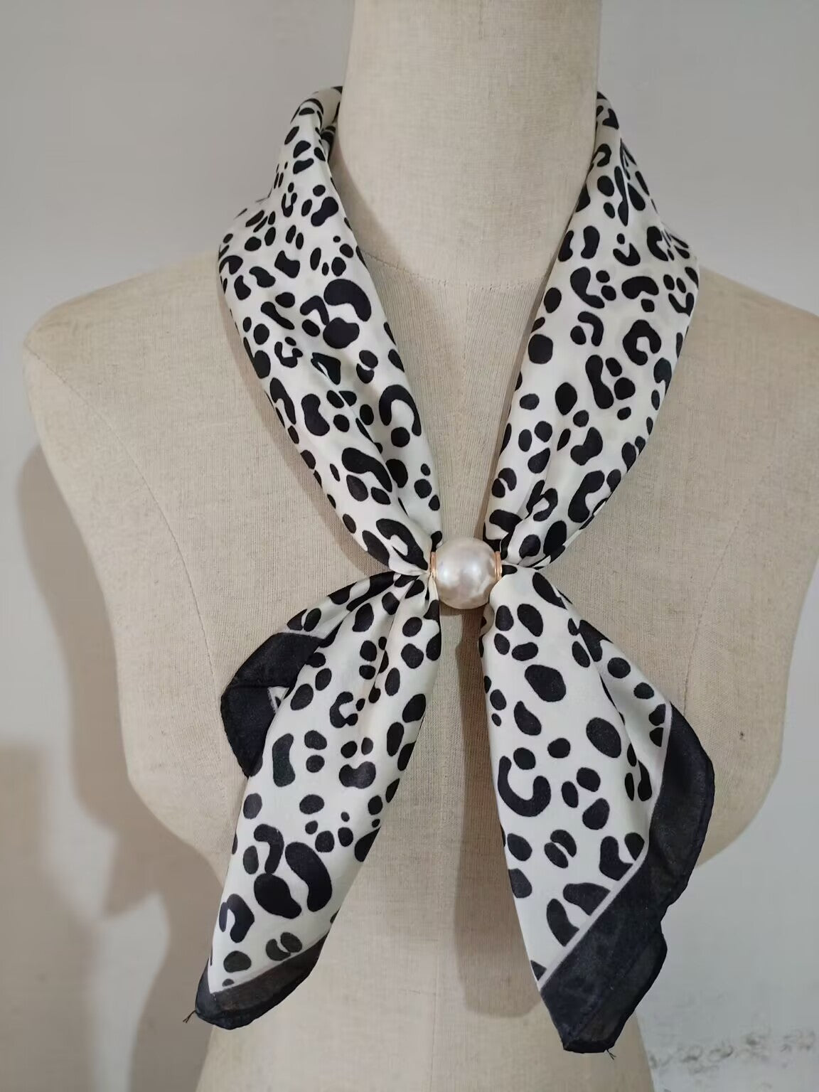 Scarf med leopardmönster i svart och vitt, knuten runt hals med pärldetalj, visad på klädningsmanikin | tim & simonsen | Lilla Hem
